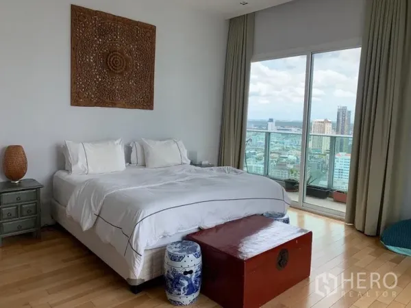 Condominium for rent in Khlong Toei, Bangkok - Master bedroom with balcony access, city view, and hardwood floors.