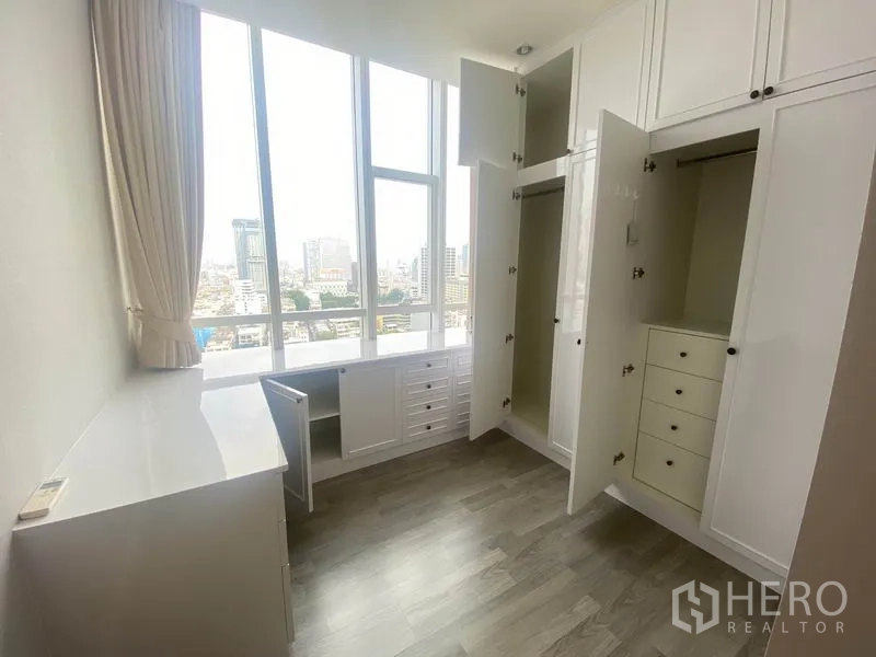 Condominium for rent in Bang Rak, Bangkok - Bedroom or dressing room with full-height wardrobes opened and a desk by the window.