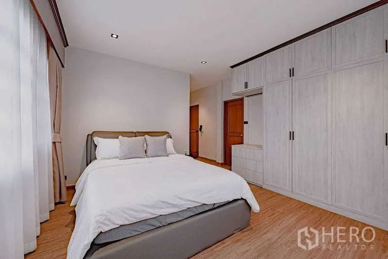 Detached House for rent or sale in Phra Khanong, Bangkok - Comfortable bedroom with white built-in wardrobes and a queen bed.