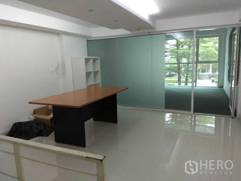 Retail Space for rent in Huai Khwang, Bangkok - Bright back office with glossy white floor, desk and a glass wall divider.