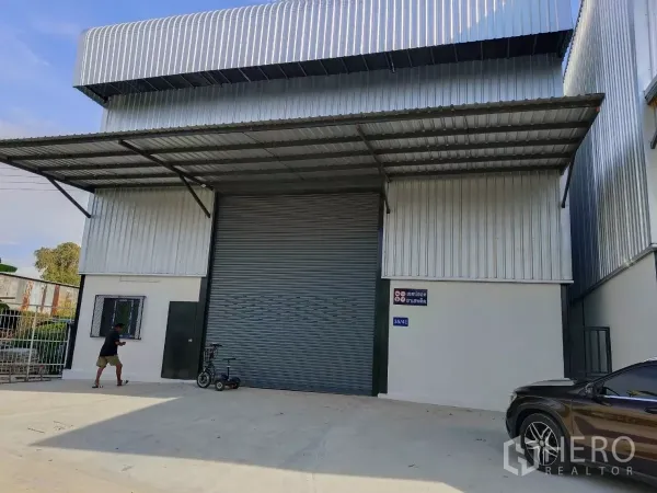 Warehouse for rent in Bang Phli, Samut Prakan - Front elevation of the warehouse showing a large roll-up door, loading apron and side window.