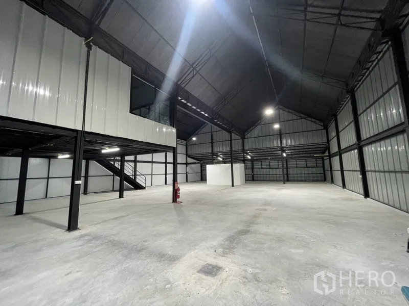 Warehouse for rent in Bueng Kum, Bangkok - Wide warehouse space with tall gable roof, metal wall panels, mezzanine office and fire safety equipment.