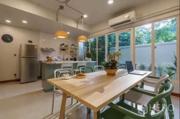 联排别墅 出租在Khlong Toei, Bangkok - 明亮餐区与开放式厨房，设岛台、吊灯与花园景观