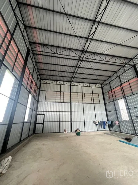 Warehouse for rent in Lam Luk Ka, Pathum Thani - High-clearance steel-frame warehouse hall with ventilation panels and a concrete floor.