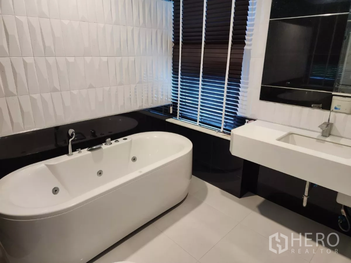 Detached House for rent or sale in Chatuchak, Bangkok - Modern bathroom with soaking bathtub, textured tile wall and wide vanity.
