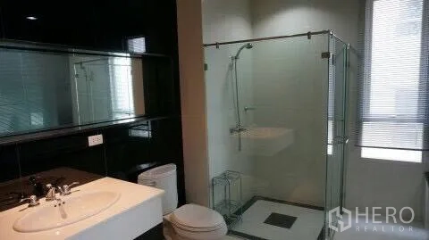 Condominium for rent or sale in Pathum Wan, Bangkok - Modern bathroom featuring a glass-enclosed shower, vanity sink and toilet