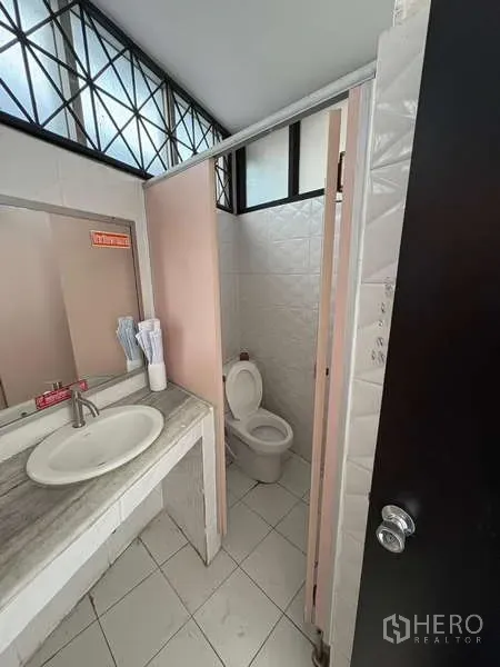 Standalone for rent in Khlong Toei, Bangkok - Compact restroom with sink and toilet cubicle in tiled finish.