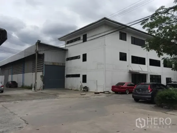 Warehouse for rent in Saphan Sung, Bangkok - Exterior view of warehouse and three-storey office building with roller shutter loading door and on-site parking.