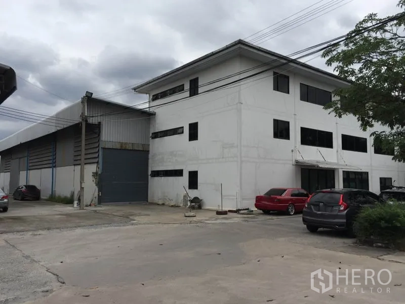 คลังสินค้า ให้เช่าในSaphan Sung, Bangkok - ภาพภายนอกโกดังพร้อมอาคารสำนักงาน 3 ชั้น ประตูม้วนโหลดสินค้า และพื้นที่จอดรถ