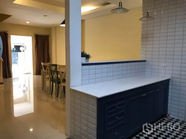 联排别墅 出租在Wang Thonglang, Bangkok - 备餐吧台，大理石台面与白色瓷砖墙，望向餐厅与前庭采光。