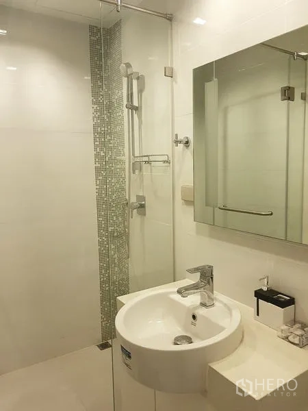 Condominium for rent in Sathon, Bangkok - Bathroom with round basin vanity, mirror cabinet and glass shower with mosaic tile accent.
