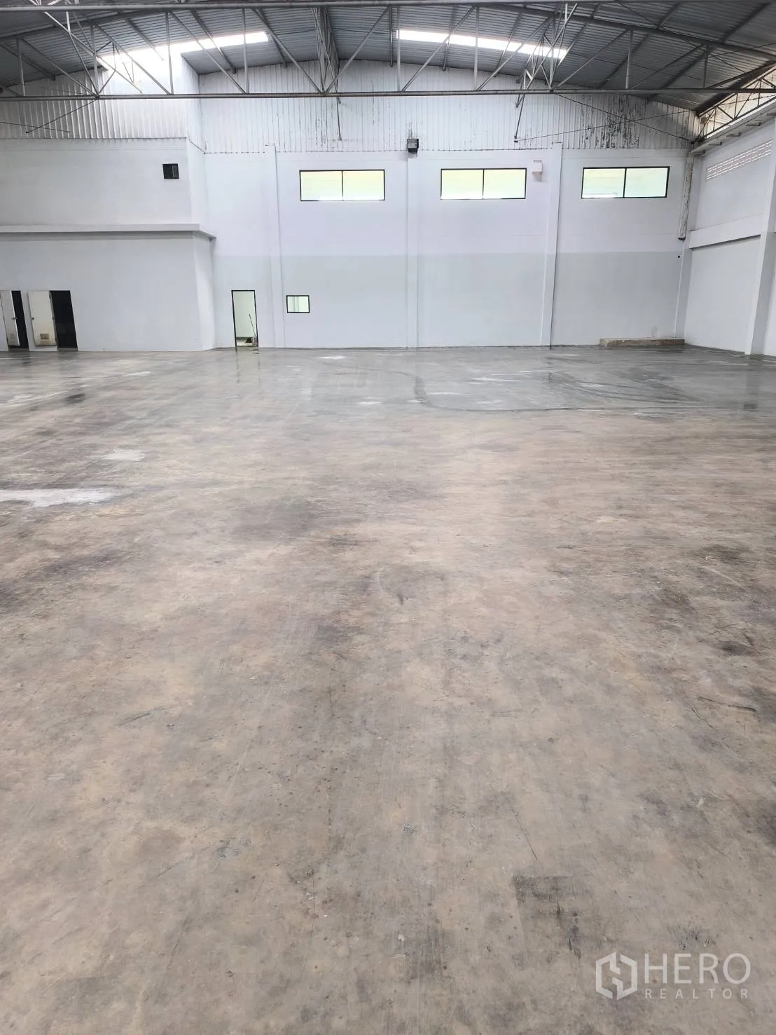 Factory for sale in Khlong Luang, Pathum Thani - Open warehouse with polished concrete floor and office block.