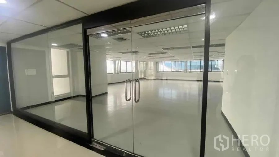 办公空间 出租或出售在Phaya Thai, Bangkok - 大面积玻璃隔断正面，空置办公套间，反光地面与日光灯。