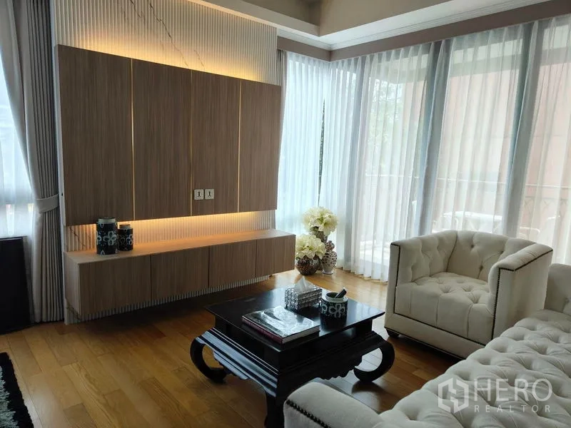 公寓 出租或出售在Pathum Wan, Bangkok - 客厅设发光的嵌入式柜体、纽扣沙发、茶几与环幕落地窗。