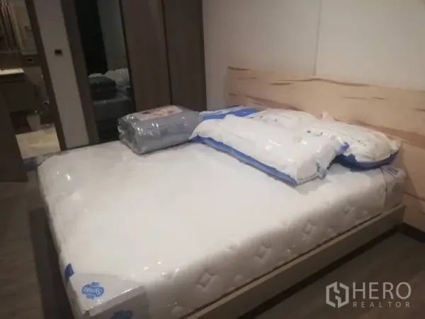 公寓 出租在Watthana, Bangkok - 卧室配新床垫与浅木色床头板，内置衣柜，可通往浴室。