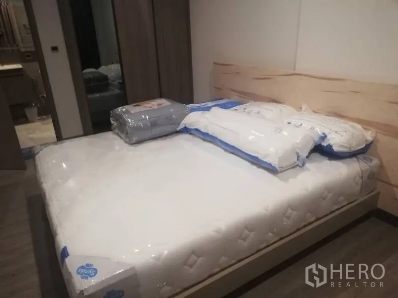 公寓 出租在Watthana, Bangkok - 卧室配新床垫与浅木色床头板，内置衣柜，可通往浴室。