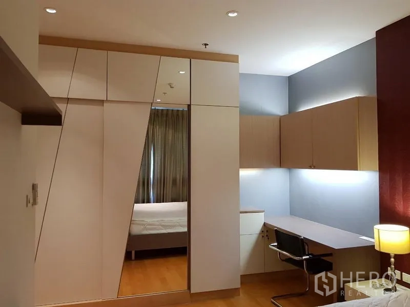 公寓 出租在Ratchathewi, Bangkok - 卧室一角设几何造型镜面衣柜与带灯长书桌。
