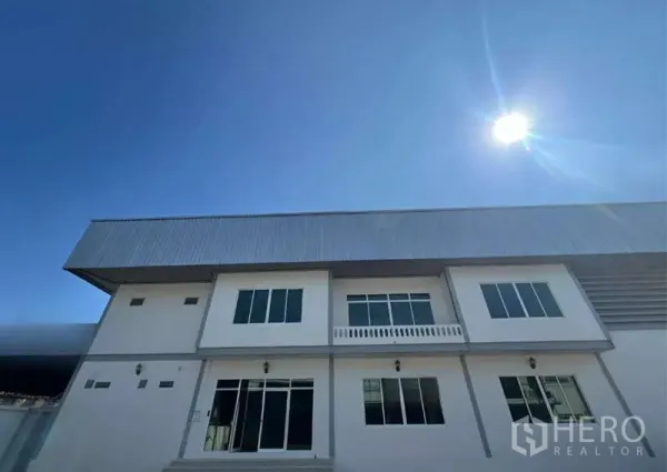 Warehouse for rent in Prawet, Bangkok - Modern two-storey warehouse facade with metal roof under a clear blue sky.