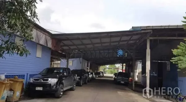 Warehouse for rent in Sai Noi, Nonthaburi - Entrance lane under metal canopy with multiple vehicles at warehouse compound