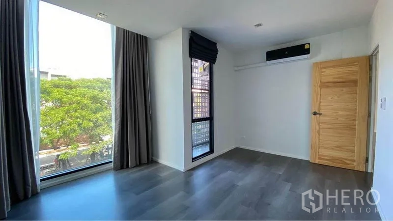 Retail Space for sale in Bang Na, Bangkok - Private room with floor‑to‑ceiling corner windows, curtains and wall‑mounted AC.