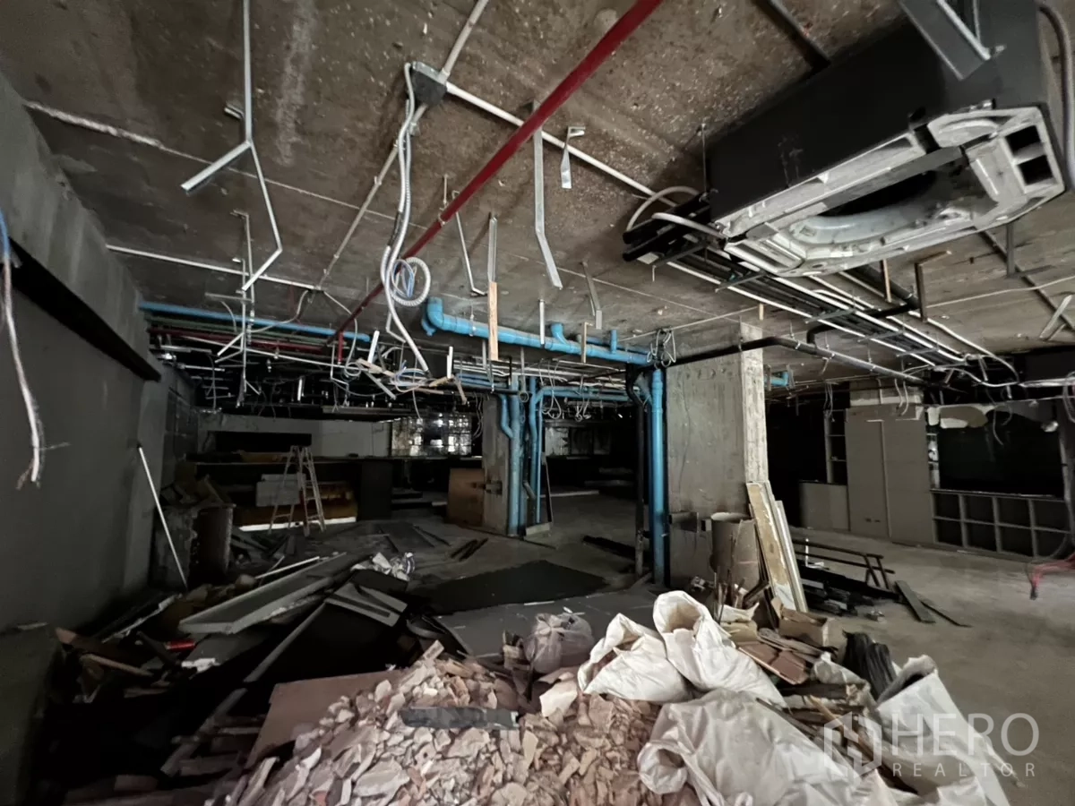 Retail Space for rent in Khlong Toei, Bangkok - Renovation debris and hanging conduits beneath an exposed concrete ceiling.