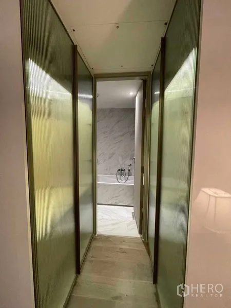 Condominium for rent in Khlong Toei, Bangkok - Narrow hallway with ribbed glass panels leading to bathroom
