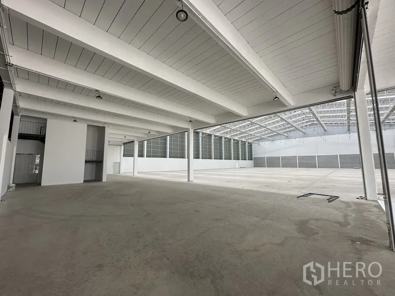 Factory for rent in Pathum Thani - Covered loading zone with beams and access to the main warehouse floor.