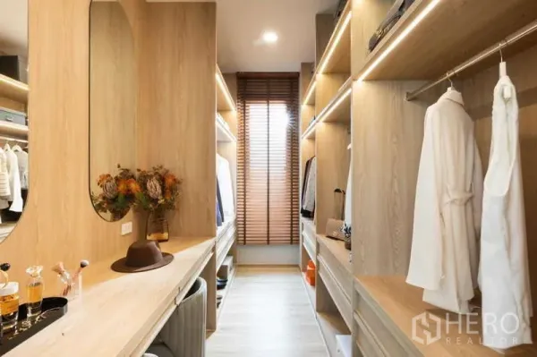 独立式住宅 出租或出售在Lat Krabang, Bangkok - 步入式衣帽间，浅木色柜体与镜面照明。