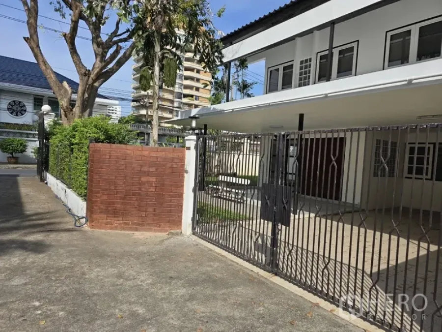 独立式住宅 出租在Watthana, Bangkok - 带滑动金属大门的入户庭院和带顶车位的独栋别墅入口。