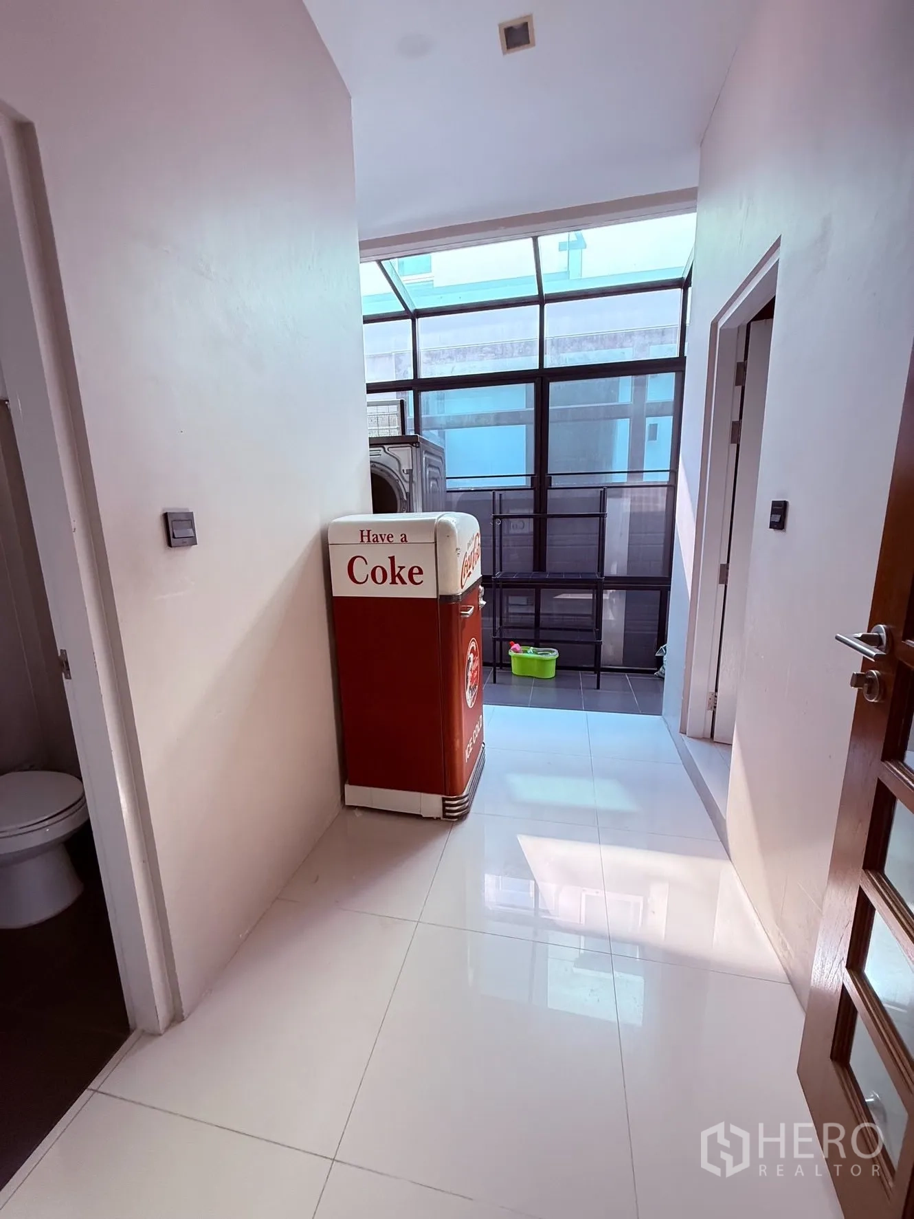 Detached House for rent or sale in Prawet, Bangkok - Hallway with skylight ceiling, retro-style fridge, and access doors to rooms and a bathroom.