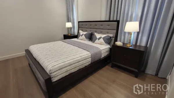 Detached House for rent or sale in Saphan Sung, Bangkok - Secondary bedroom with dark wood bedframe, twin nightstands and warm floors.
