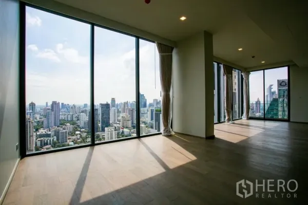 Condominium for rent in Watthana, Bangkok - Corner living space with tall glass walls showcasing a panoramic skyline.