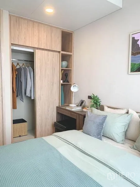 Condominium for sale in Khlong Toei, Bangkok - Cozy bedroom with built-in wardrobe, open shelving, and a small work desk in light wood.