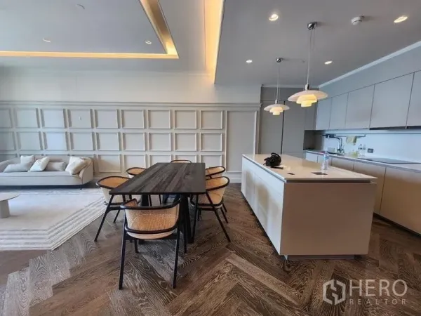 Condominium for sale - Open-plan living with dining table beside an island kitchen and soft tray-ceiling lighting.