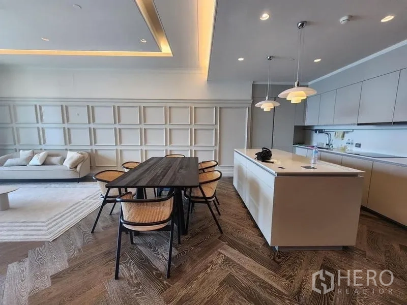 Condominium for sale - Open-plan living with dining table beside an island kitchen and soft tray-ceiling lighting.