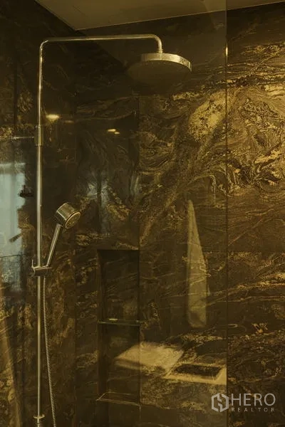 Condominium for rent in Bang Rak, Bangkok - Rain shower and handheld shower set in a marble-tiled glass cubicle.
