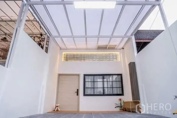 联排别墅 出租在Khlong Toei, Bangkok - 带白色金属顶棚的前院车位，配窗户与入户门