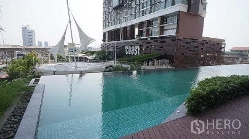 Condominium for sale in Bang Na, Bangkok - Condominium outdoor infinity-edge swimming pool with deck and a city backdrop.