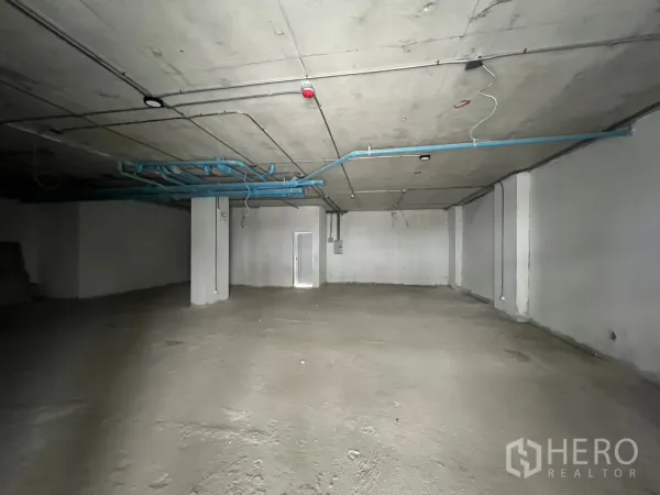 零售空间 出租 - 开放式平面，结构柱与可见管道，适合租户自行装修。