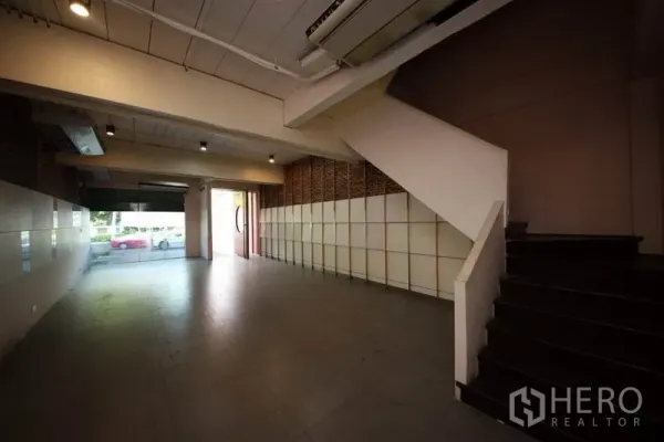 带办公室的家 出租或出售在Huai Khwang, Bangkok - 一层开放式空间，带楼梯、射灯和大幅临街玻璃门窗。