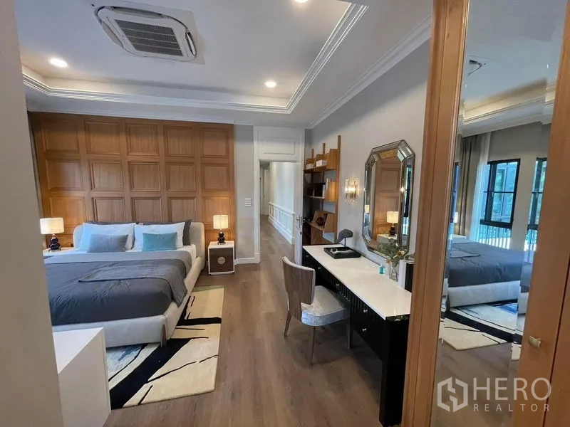 Detached House for rent or sale in Saphan Sung, Bangkok - Spacious master bedroom with wood panel headboard, writing desk and built-in shelving.