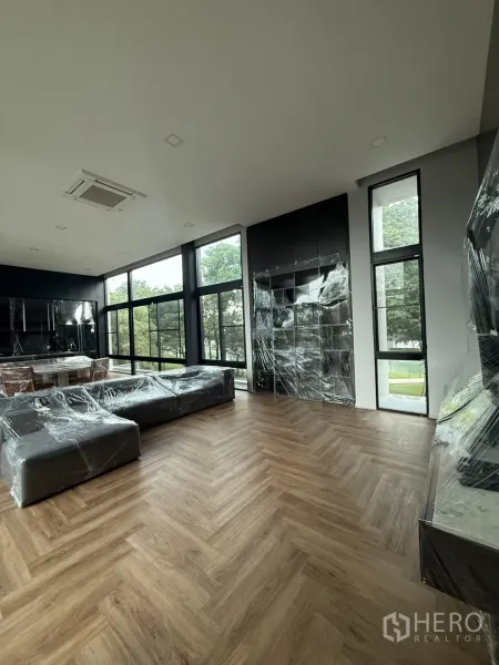 Detached House for rent in Saphan Sung, Bangkok - Living area highlighting a black feature wall, large windows and warm wood flooring.