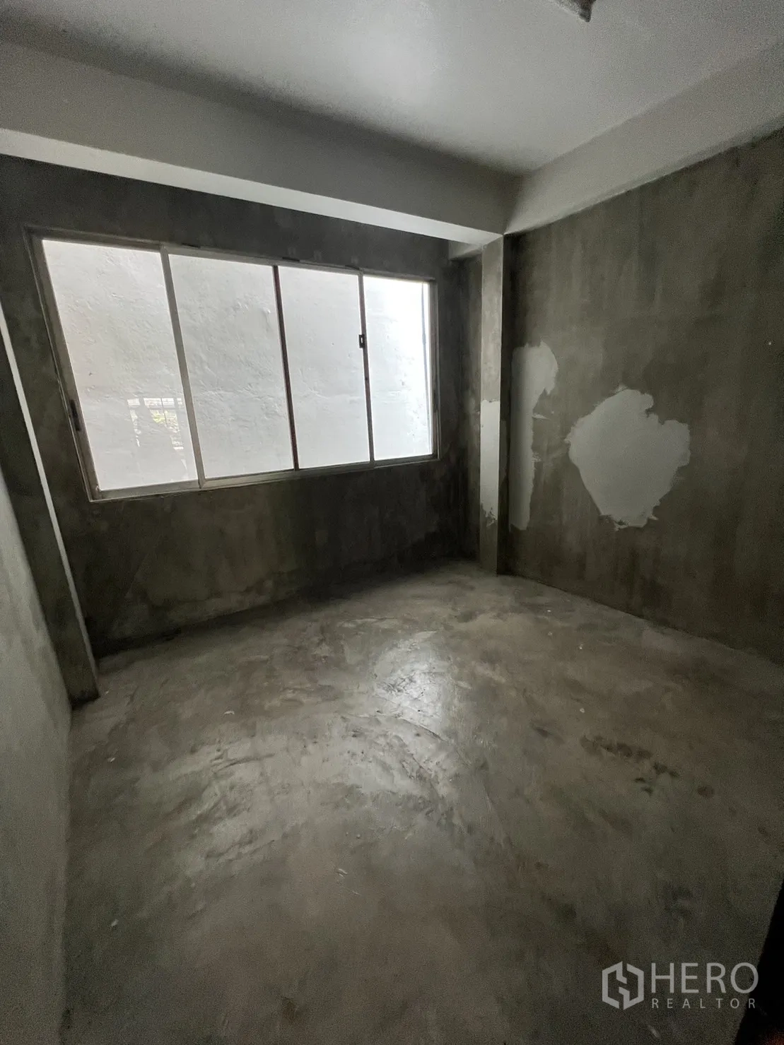 Shophouse for rent in Watthana, Bangkok - Raw concrete room with wide frosted window.