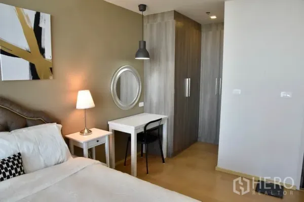 Condominium for rent in Phaya Thai, Bangkok - Bedroom corner featuring study desk, wall mirror, wardrobe, and warm bedside lighting.