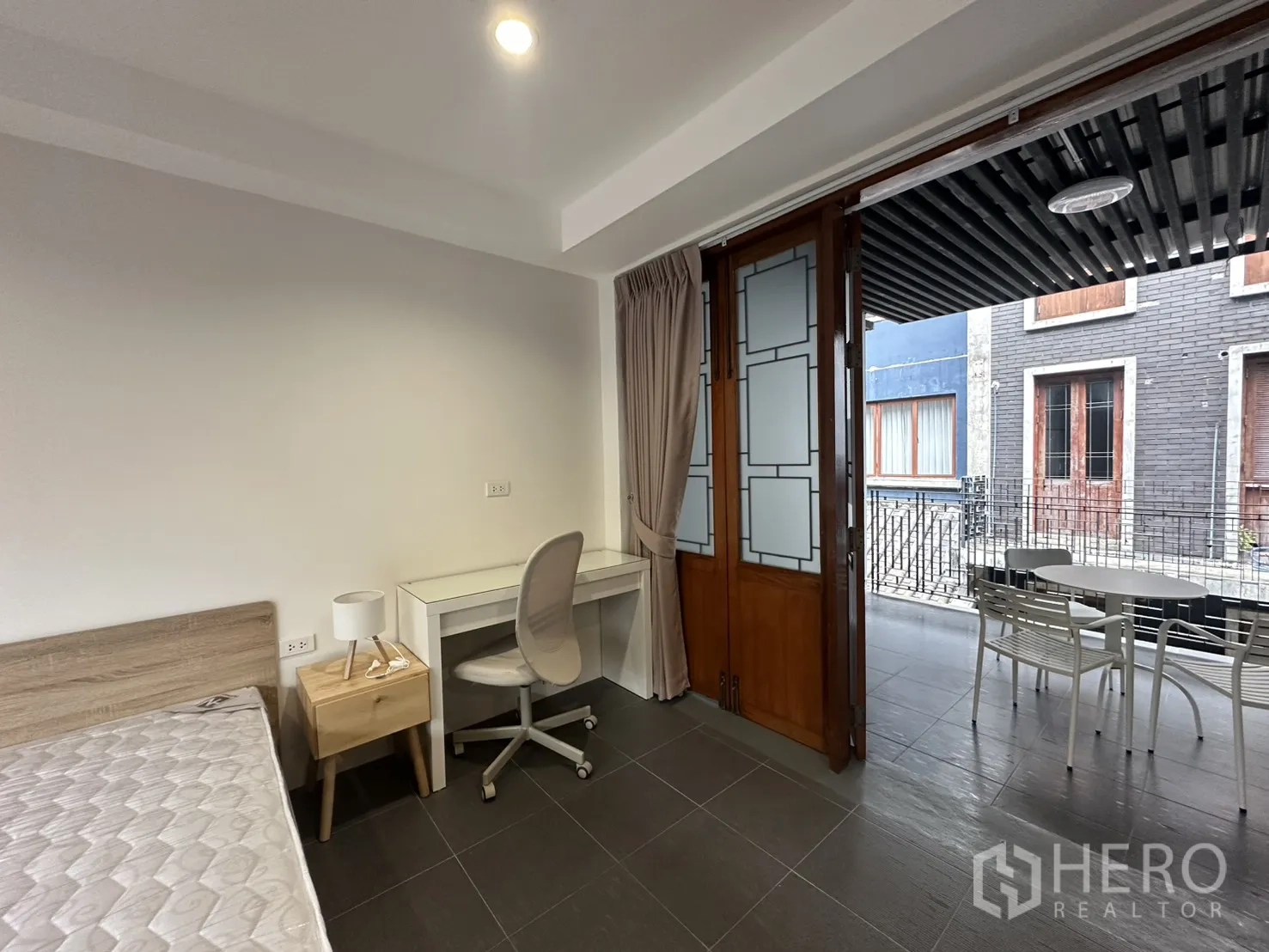 公寓 for rent in Pathum Wan, Bangkok - 遮蔽露台设小圆桌与白色椅子，眺望内侧立面。