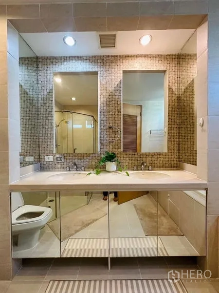 Condominium for rent in Bang Rak, Bangkok - Double-sink vanity with mosaic feature wall and mirrored storage cabinets.