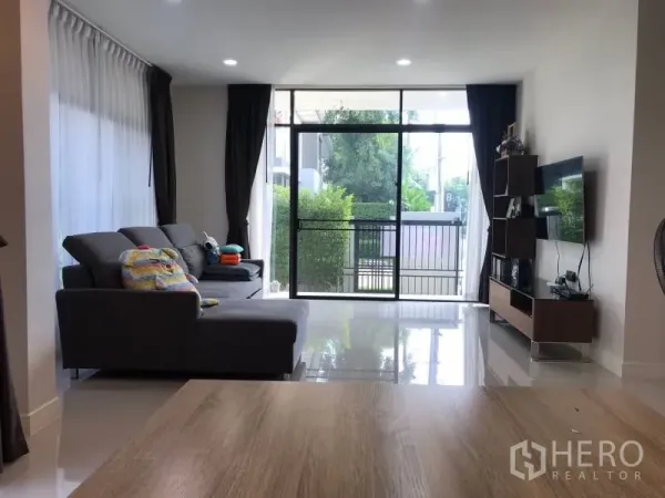 บ้าน ให้เช่าในBang Kapi, Bangkok - ห้องนั่งเล่นสว่างด้วยประตูกระจกเต็มบาน โซฟาสีเทา และชั้นวางทีวี