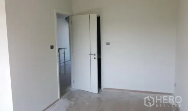 Townhouse for rent in Bueng Kum, Bangkok - Empty bedroom with an open white door and smooth floors ready for fit-out.