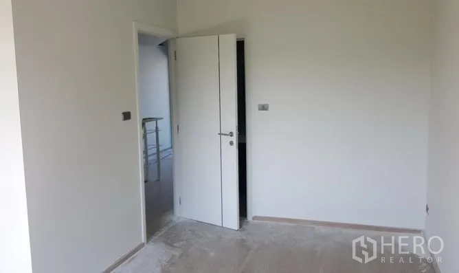 Townhouse for rent in Bueng Kum, Bangkok - Empty bedroom with an open white door and smooth floors ready for fit-out.