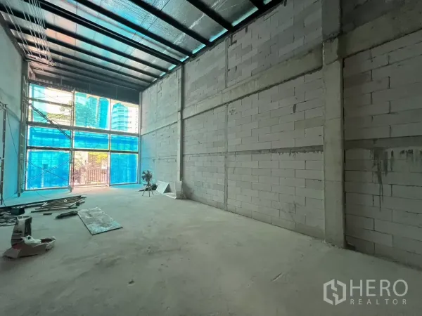 零售空间 出租在Khlong Toei, Bangkok - 挑高毛坯空间，暴露天花与蓝色临时窗膜